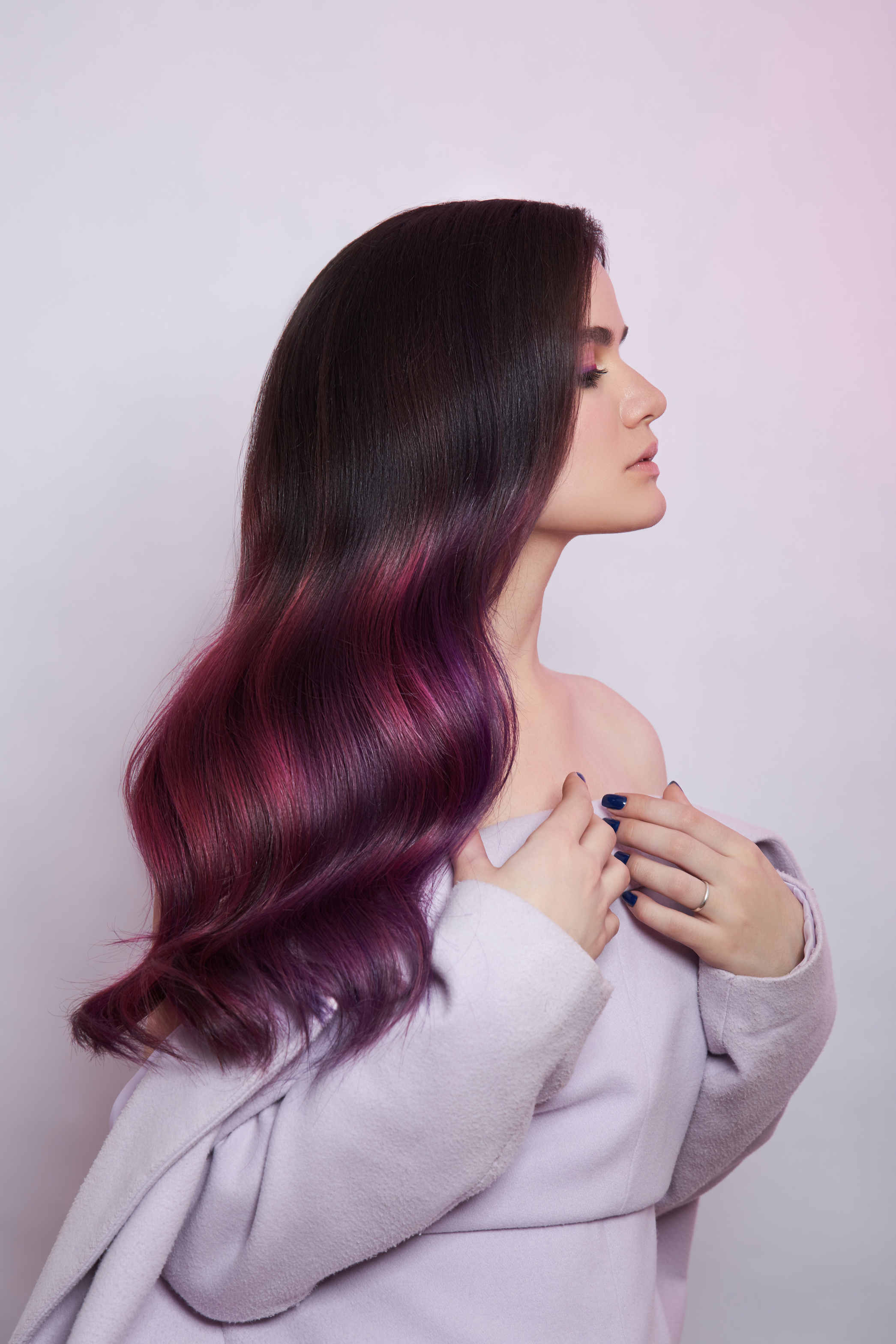 Portrait of a woman with bright colored flying hair, all shades of purple. Shiny Healthy colored Hair coloring, beautiful lips and makeup. Sexy girl with long hair styling