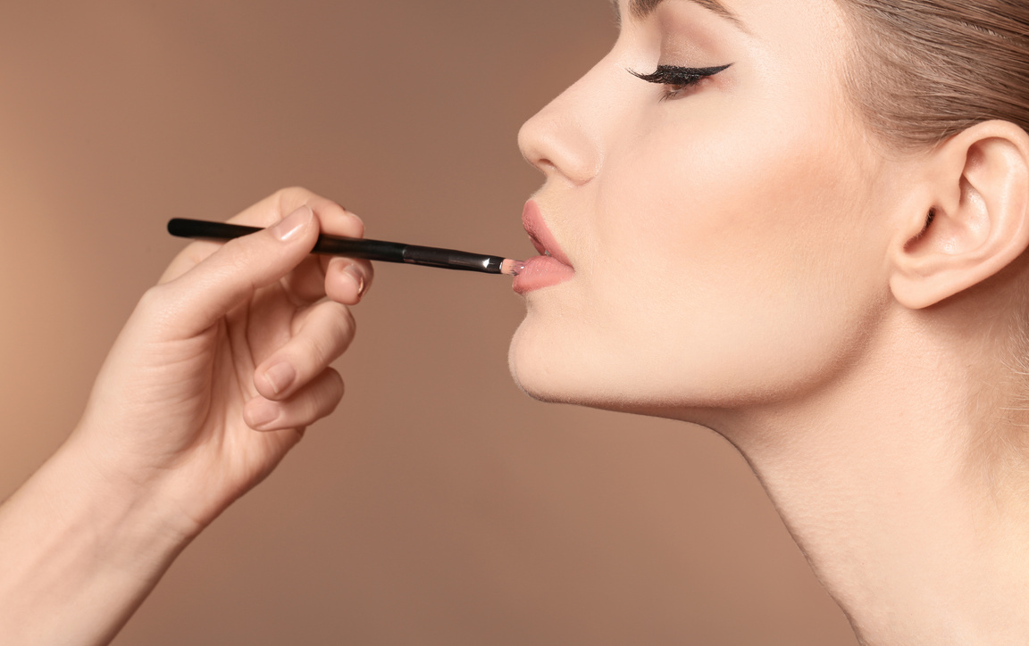 Make-up Artist Applying Makeup on Woman's Face on Beige Background